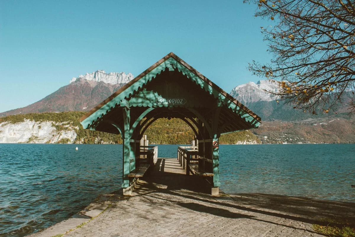 Wooden pavilion on the shore of a lake with mountains in the background