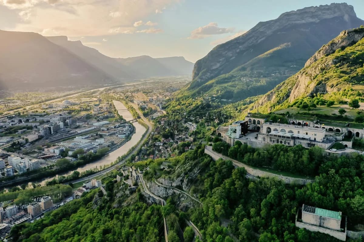 Aerial view of a valley with towns and green slopes below the mountains