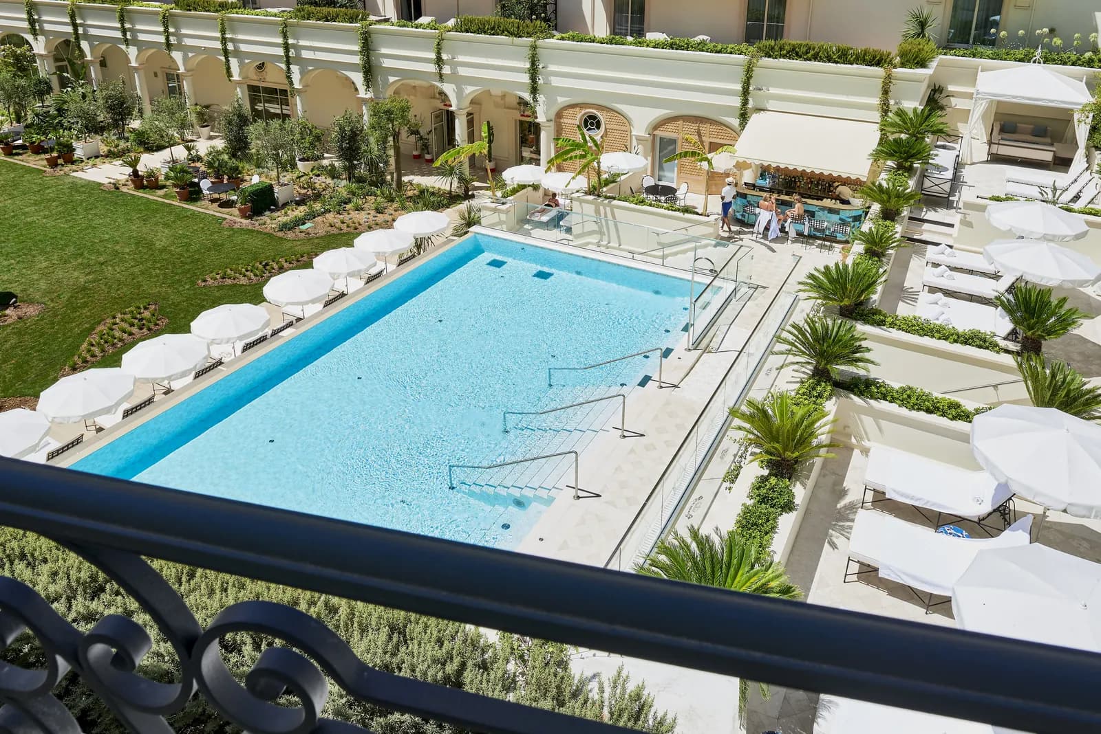 Outdoor pool with white parasols and sun loungers at Carlton Cannes, a Regent Hotel
