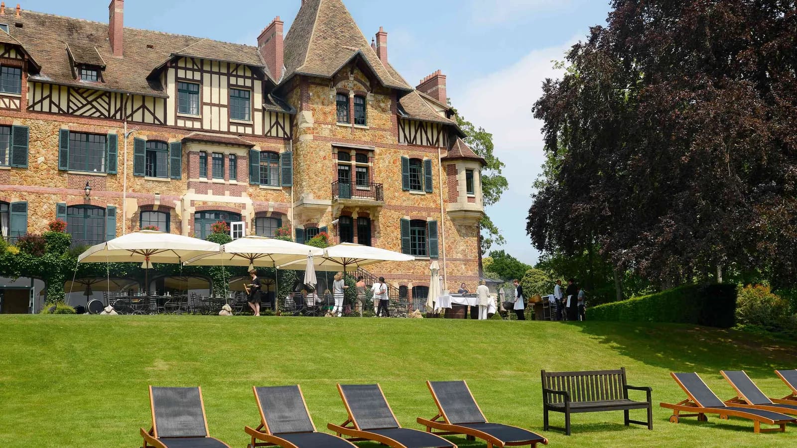Half-timbered château with a lawn, loungers and parasols at Château des Berges Sereines, Yvelines