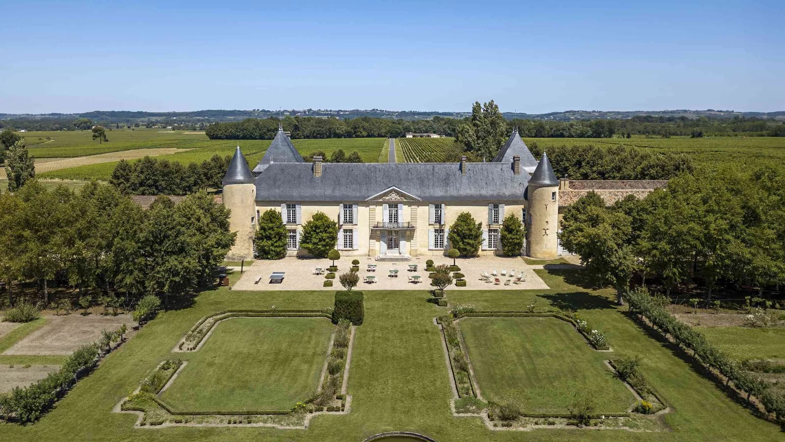 Aerial view of the château and its formal gardens among vineyards at Château des Coteaux Ambrés, Gironde