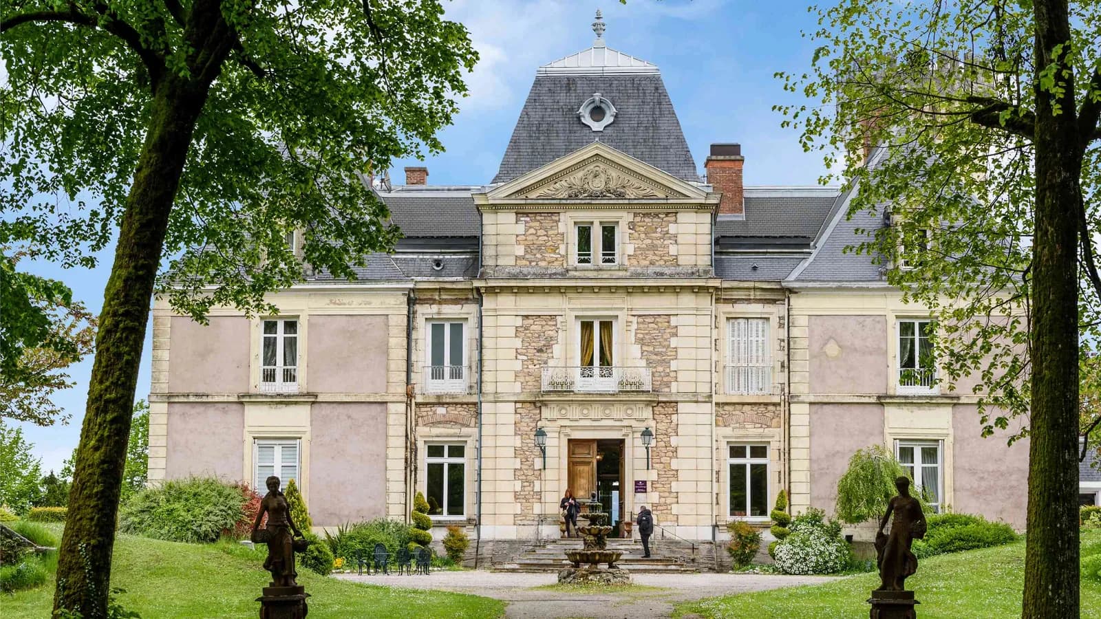 Château facade framed by tall trees at Château des Quatre Vents, Isère, east of Lyon