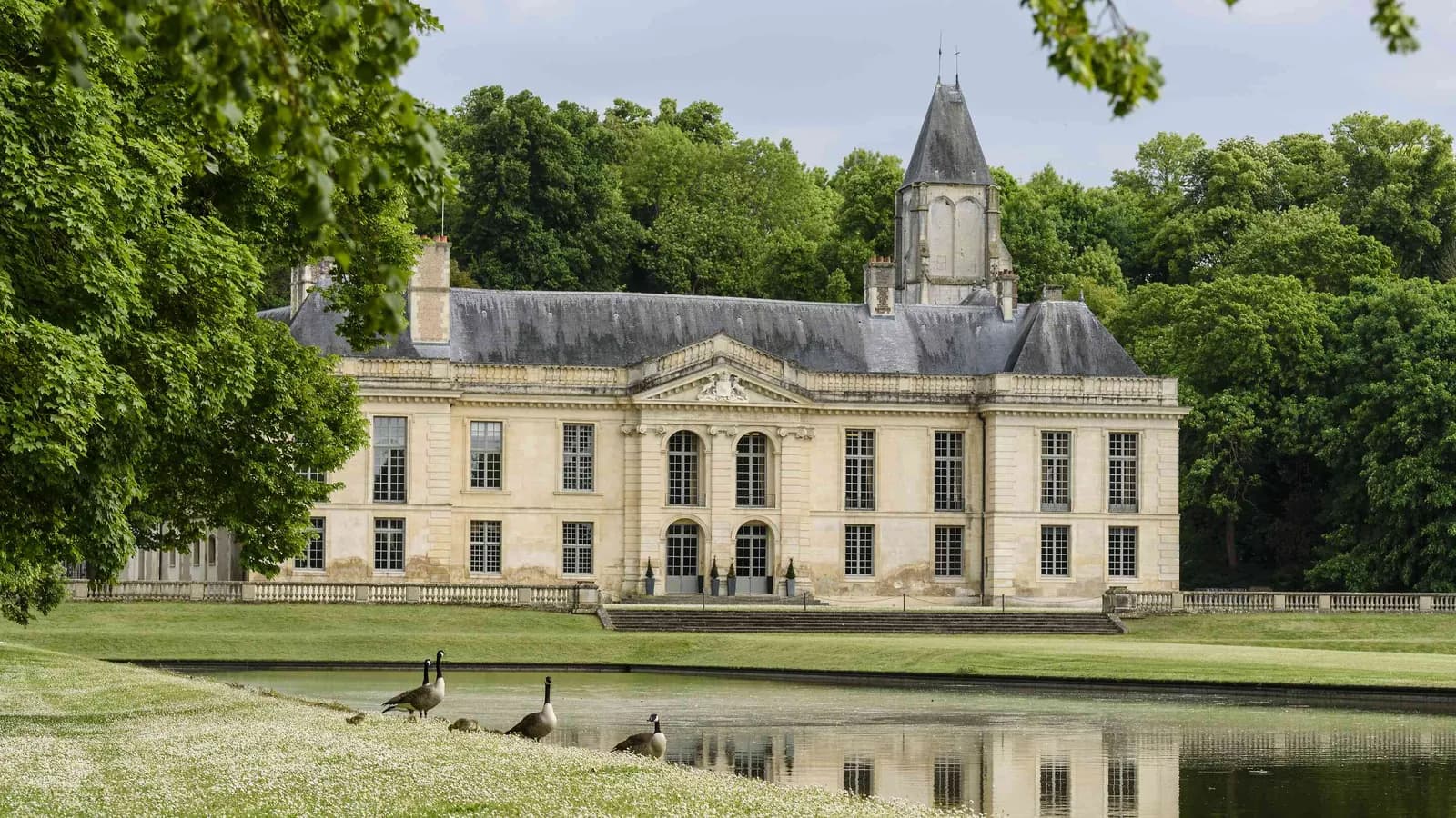 Château with a tower and reflecting lake at Château des Rives Claires in the Val-d'Oise