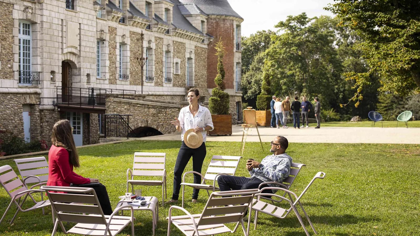 Stone château with lawns and guests chatting outdoors at Château des Sentes Vives, Yvelines
