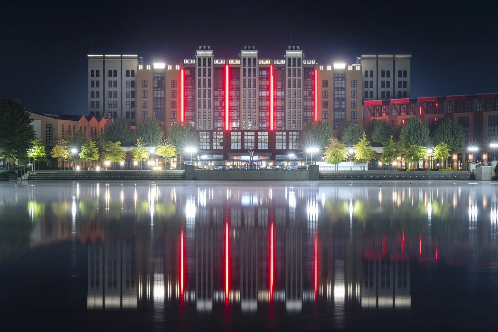 Illuminated exterior of Disney's Newport Bay Club at night, reflected in the lake at Disneyland Paris