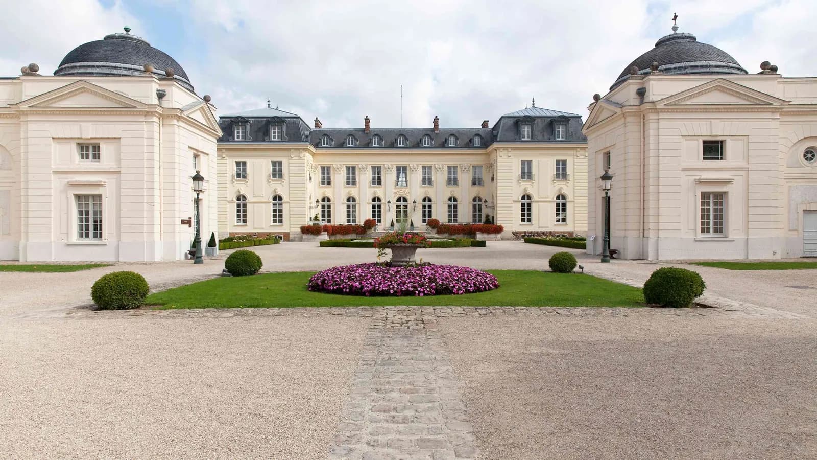 Domed château facade with a central fountain and clipped lawns at Domaine de la Haute Futaie, Yvelines