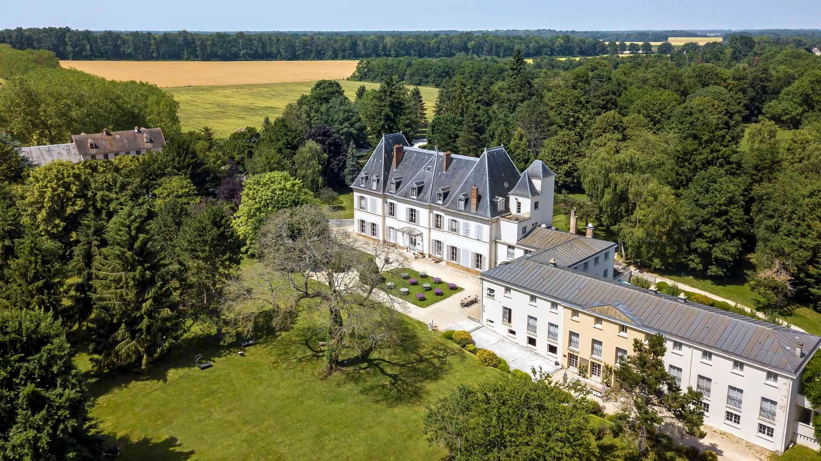 Aerial view of Domaine des Herbes Folles, a château with its wings and gardens in Seine-et-Marne