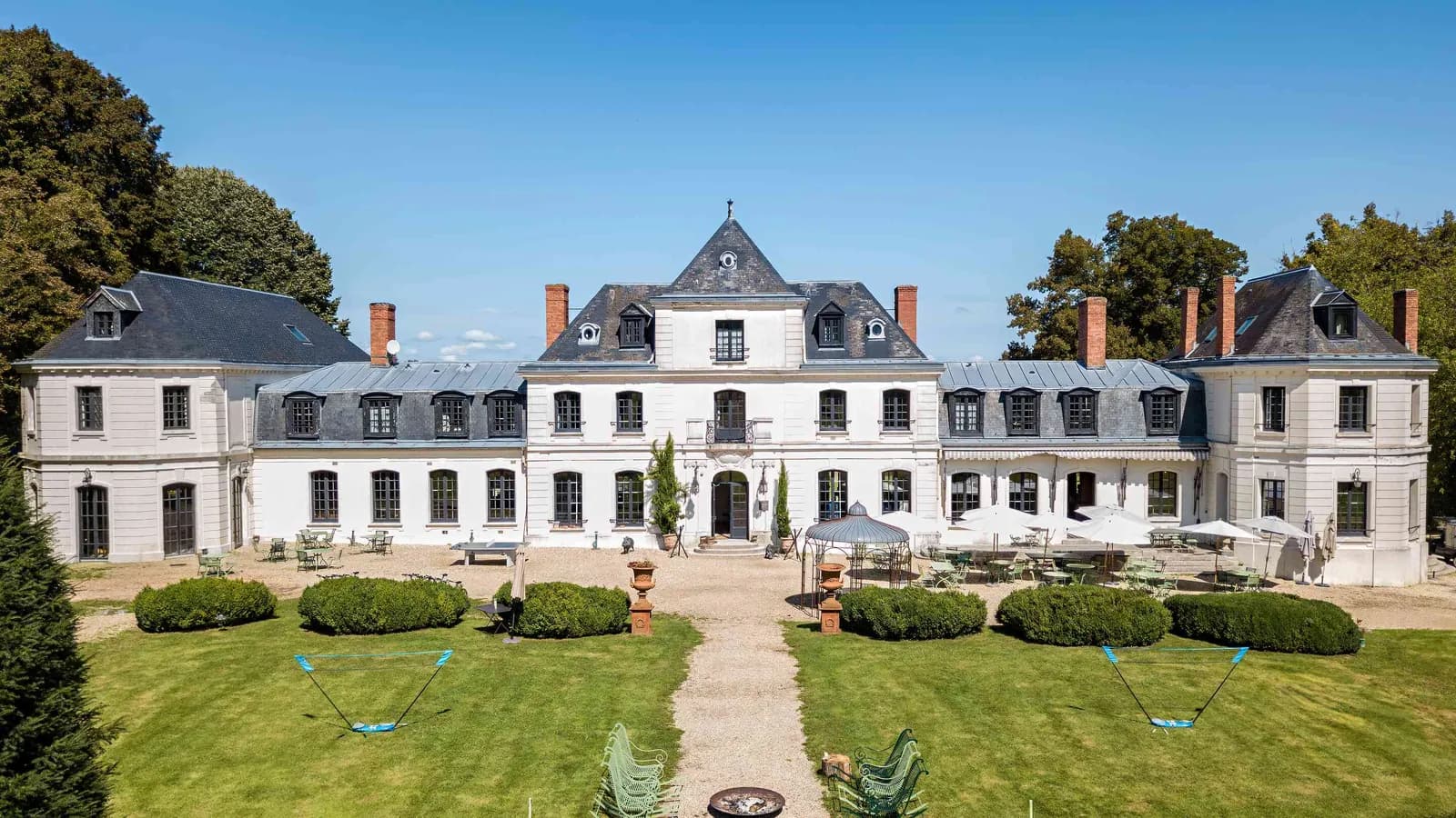 Château facade on a wide lawn beside formal gardens at Domaine des Hêtres Clairs, Eure, Normandy