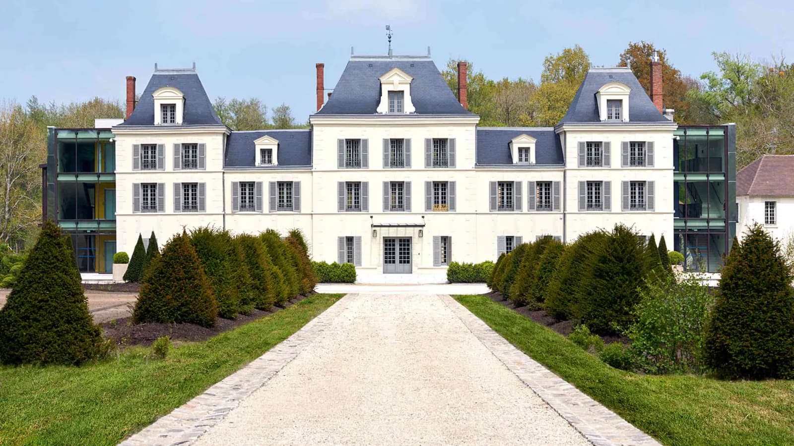Château facade with a gravel approach and clipped hedges at Domaine des Sources Vertes, Yvelines