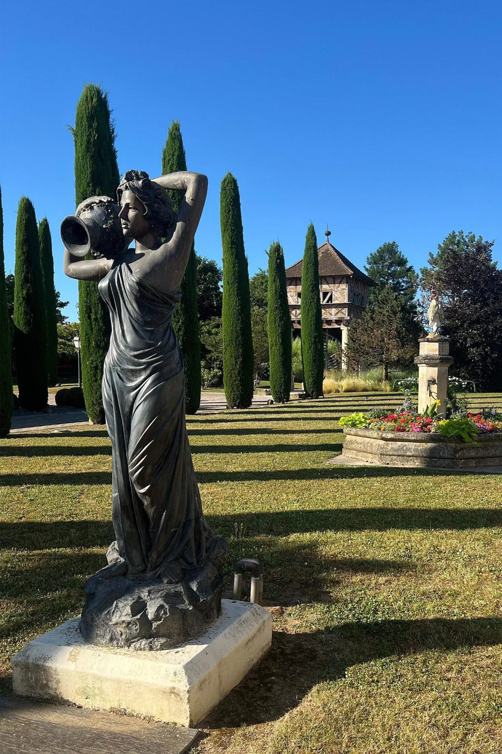 Bronze statue and clipped cypresses in the sculpted garden grounds of Georges Blanc Parc & Spa in Vonnas