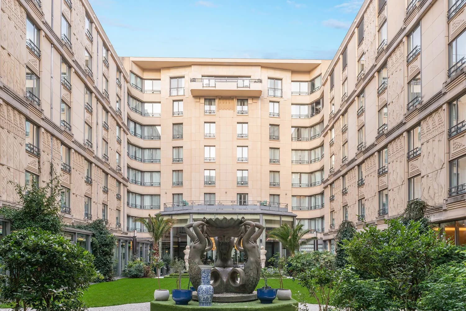 Courtyard garden and stone facade of the Hôtel du Collectionneur Arc de Triomphe, with a bronze sculpture