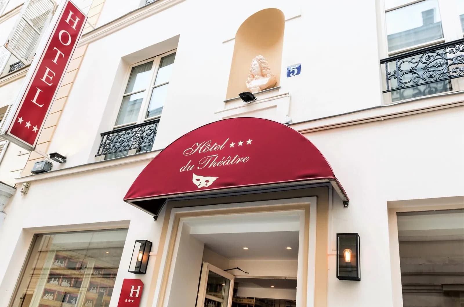 Street entrance of Hôtel du Théâtre in Paris's 17th arrondissement, with a red awning and a three-star sign