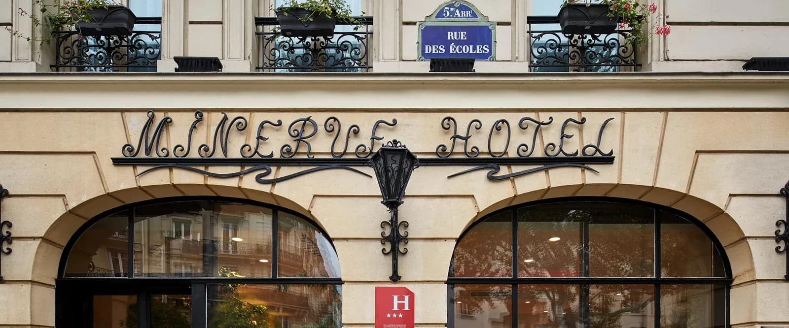 Façade of Hôtel Minerve Paris on rue des Écoles in the 5th arrondissement, with its wrought-iron hotel sign
