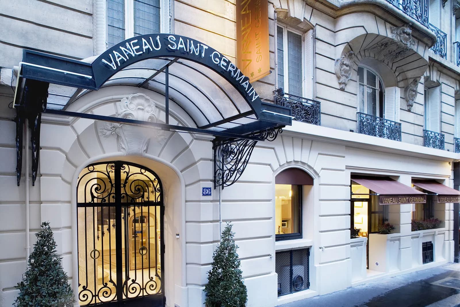 Façade of Hôtel Vaneau Saint-Germain in Paris, with its arched navy awning and wrought-iron entrance gate
