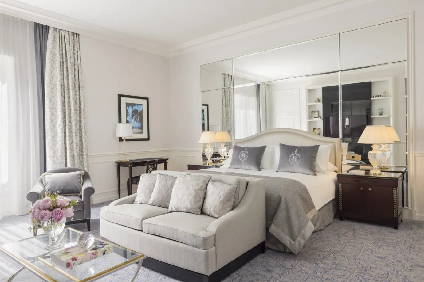 Junior suite with grey sofa, mirrored wardrobes and a glass coffee table at InterContinental Paris Le Grand