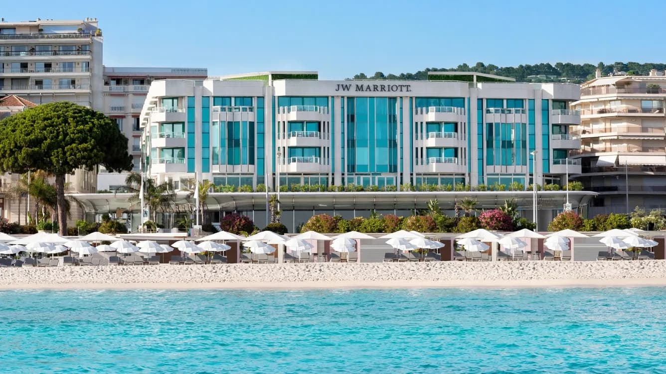 Exterior of JW Marriott Cannes on the Croisette with its turquoise pool and beach parasols