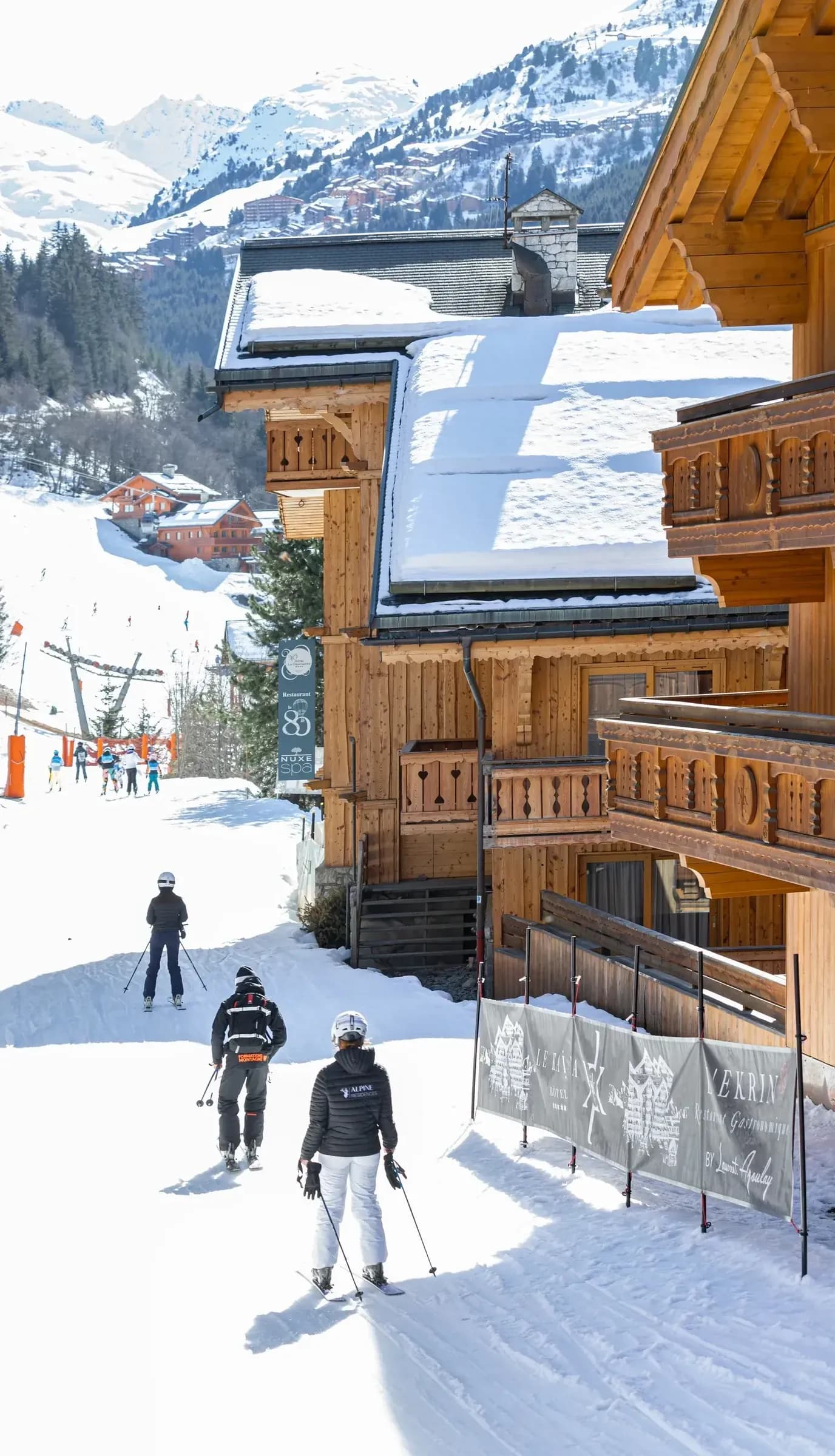 Timber chalet facade with wooden balconies above the snowy slope at Le Kaïla, Méribel