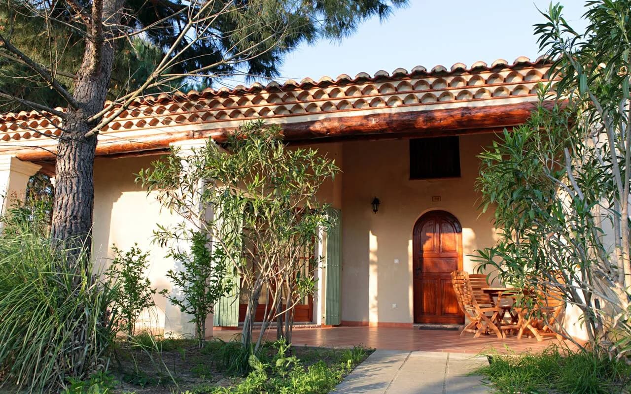 Low terracotta-roofed building with an arched entrance among pine trees at Le Mas des Sables