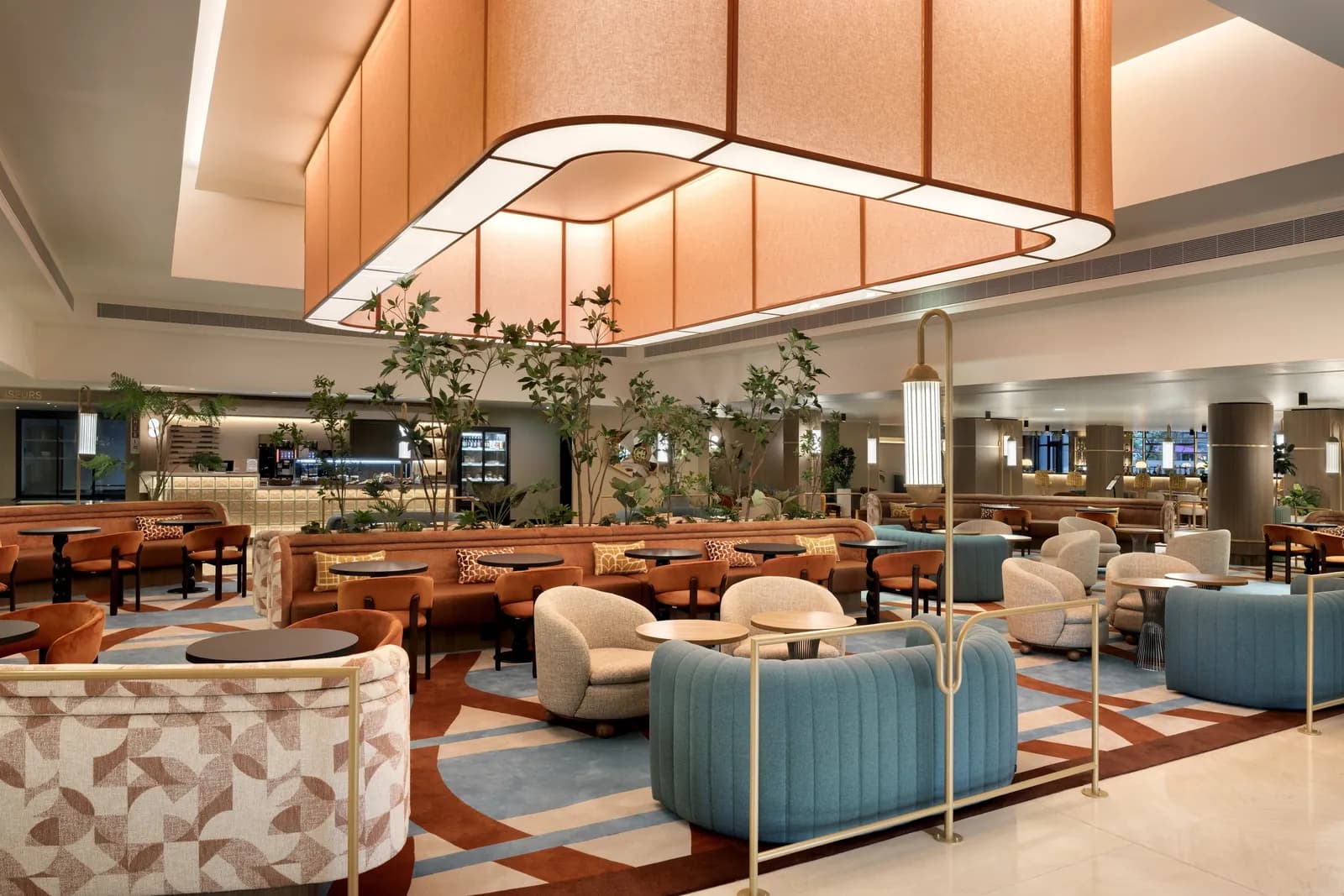 Lounge with blue armchairs and a sculptural pendant light at Le Méridien Étoile, Paris
