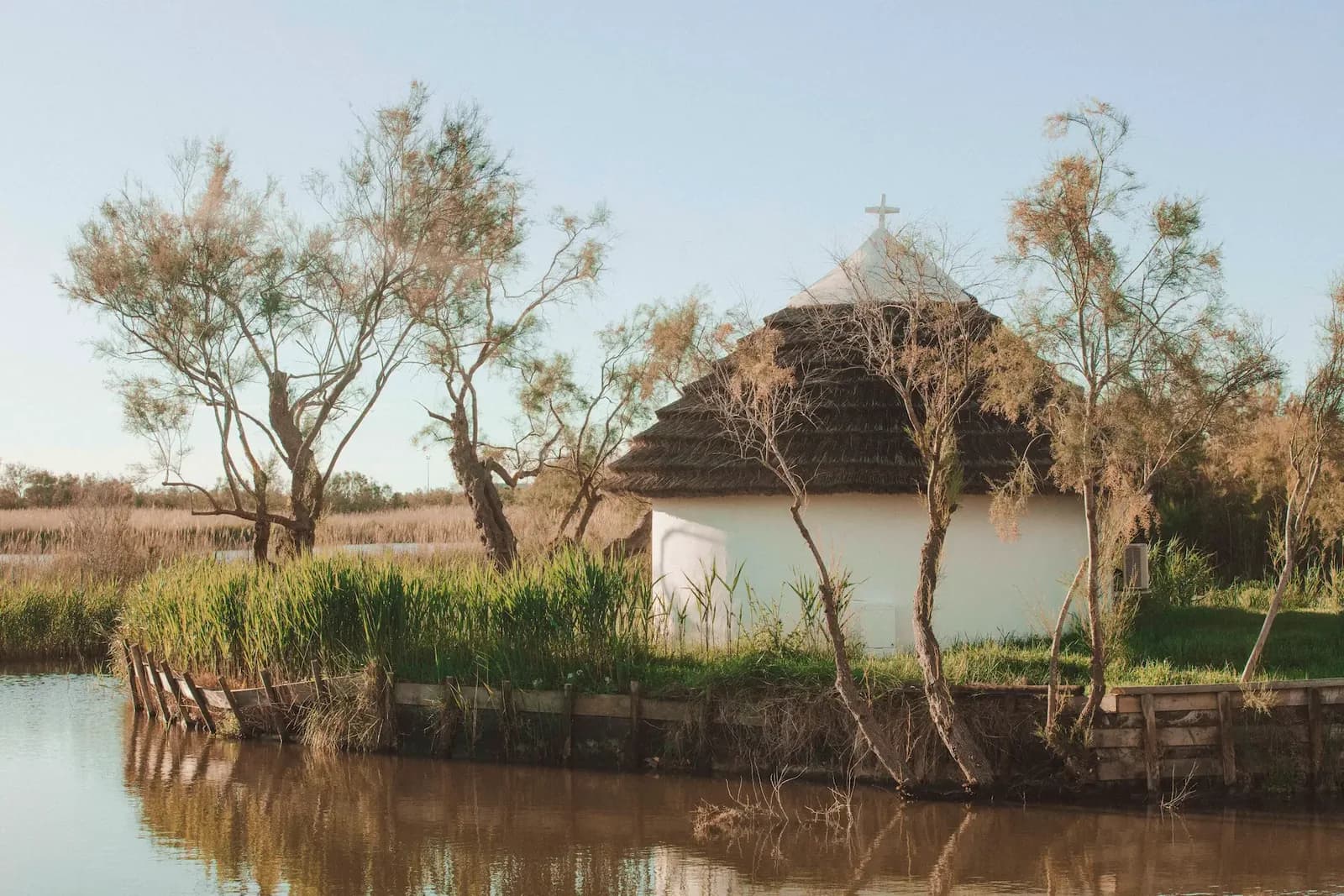 Traditional thatched cabin by the water and reed beds at Les Bains Gardians in the Camargue