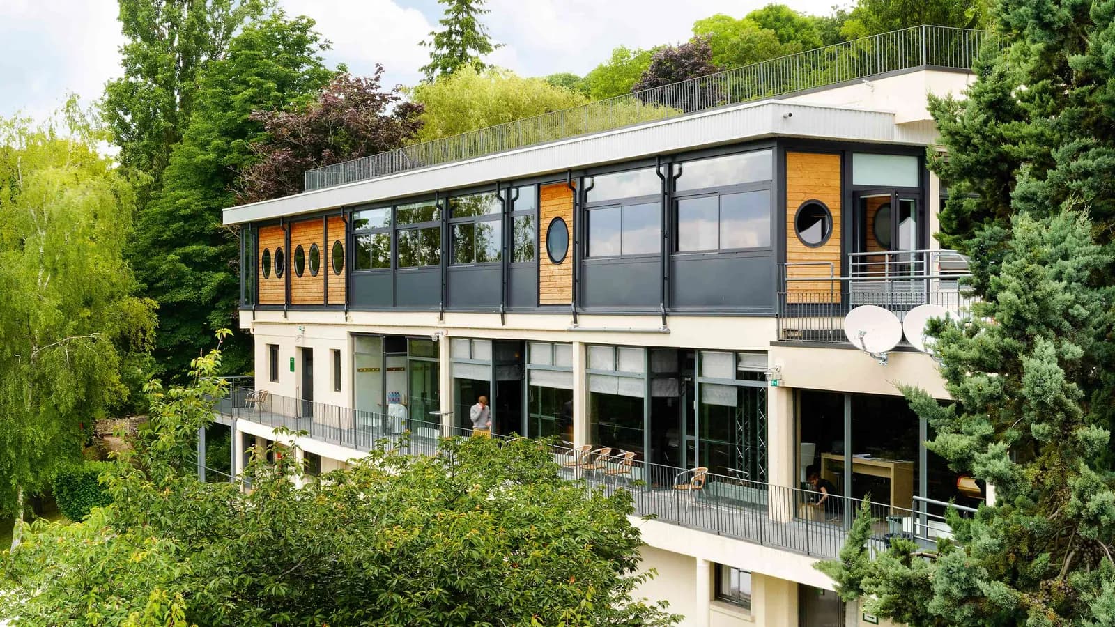 Exterior of Les Jardins du Fleuve seminar campus in Seine-et-Marne, a two-storey building framed by tall trees