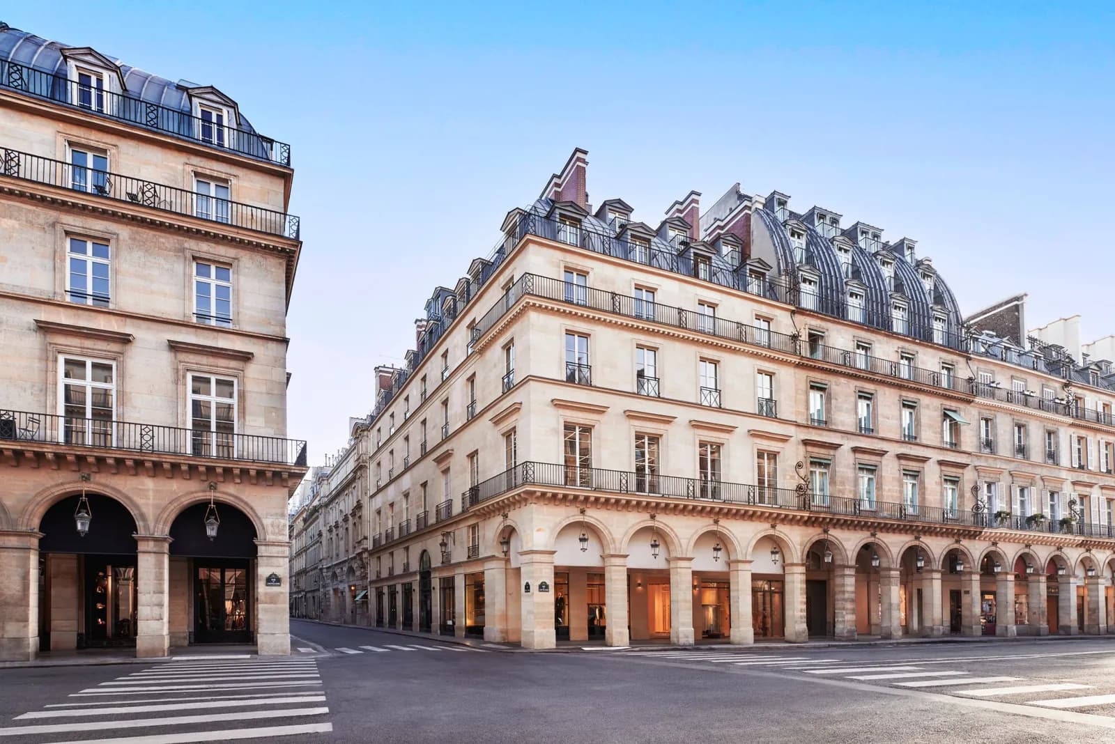 Stone facade of Maison Barrière Vendôme on a sunlit Paris corner, with arcades and mansard roofs