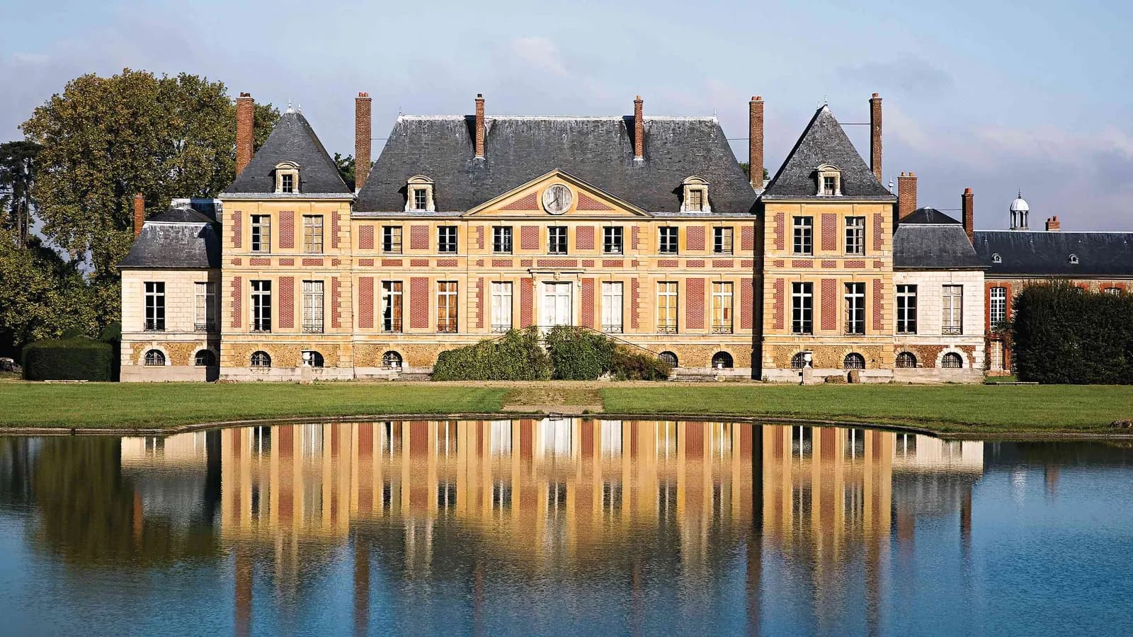 Château with a reflecting pond and wooded grounds at Manoir des Saules Dorés, Seine-et-Marne