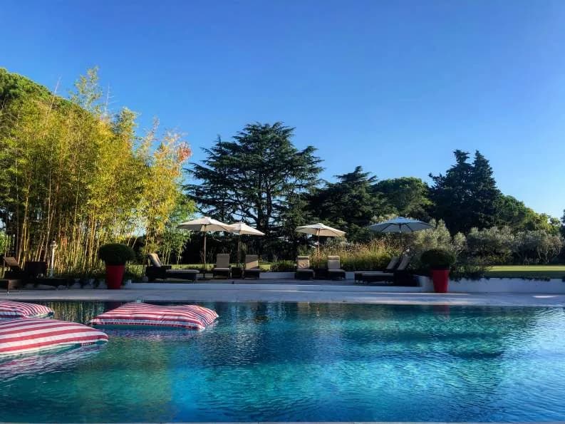 Blue swimming pool bordered by greenery at Mas de l'Espérance, Gard Camargue