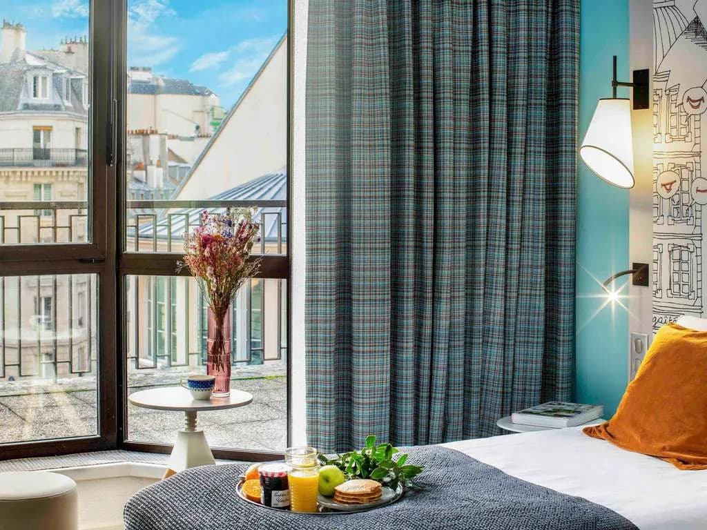 Bedroom with a Paris rooftop view and a breakfast tray at Mercure Paris Centre Gare Montparnasse, Paris