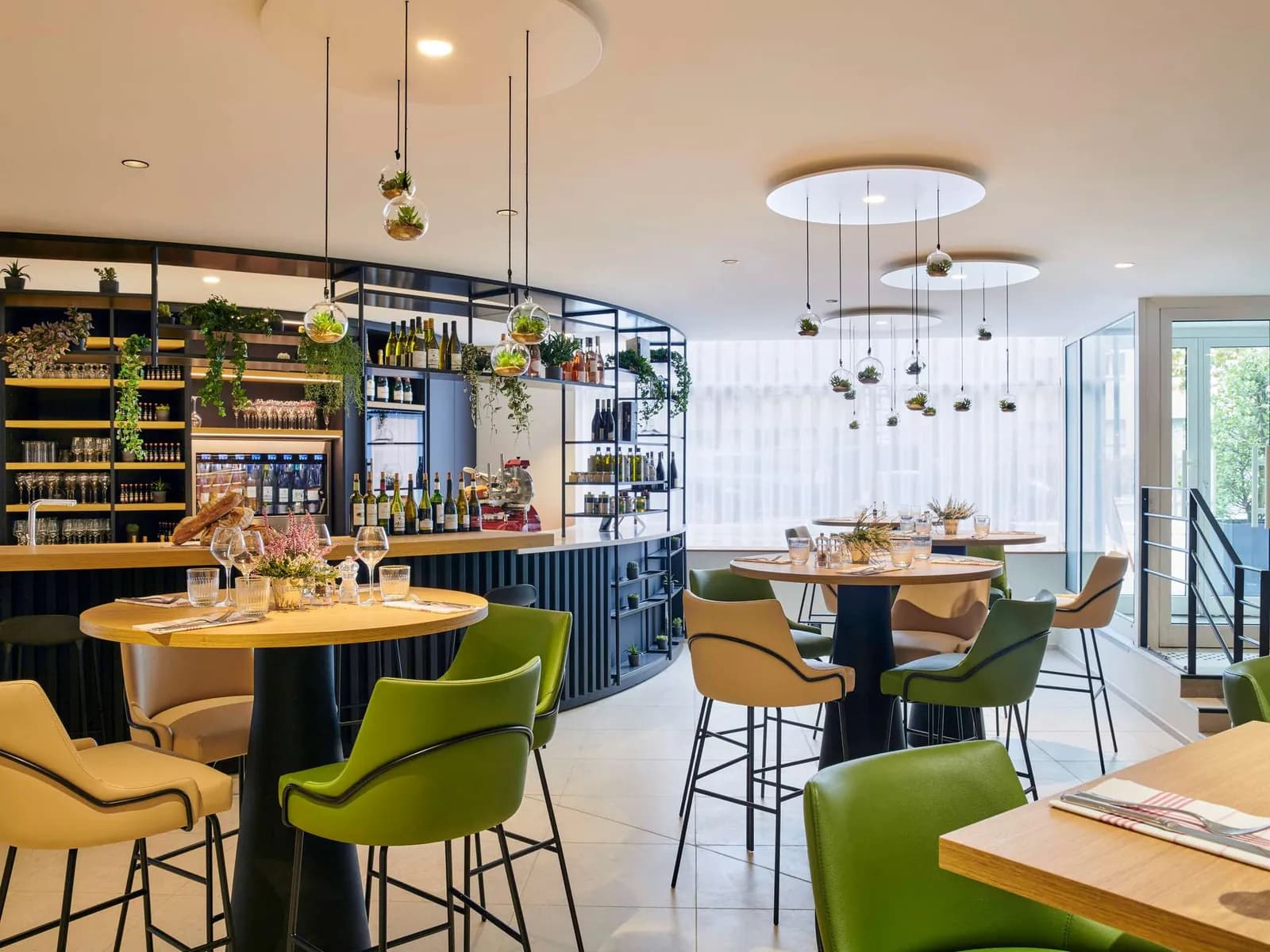 Bar and lounge with pendant lights, round tables and green chairs at Mercure Paris La Défense, Courbevoie