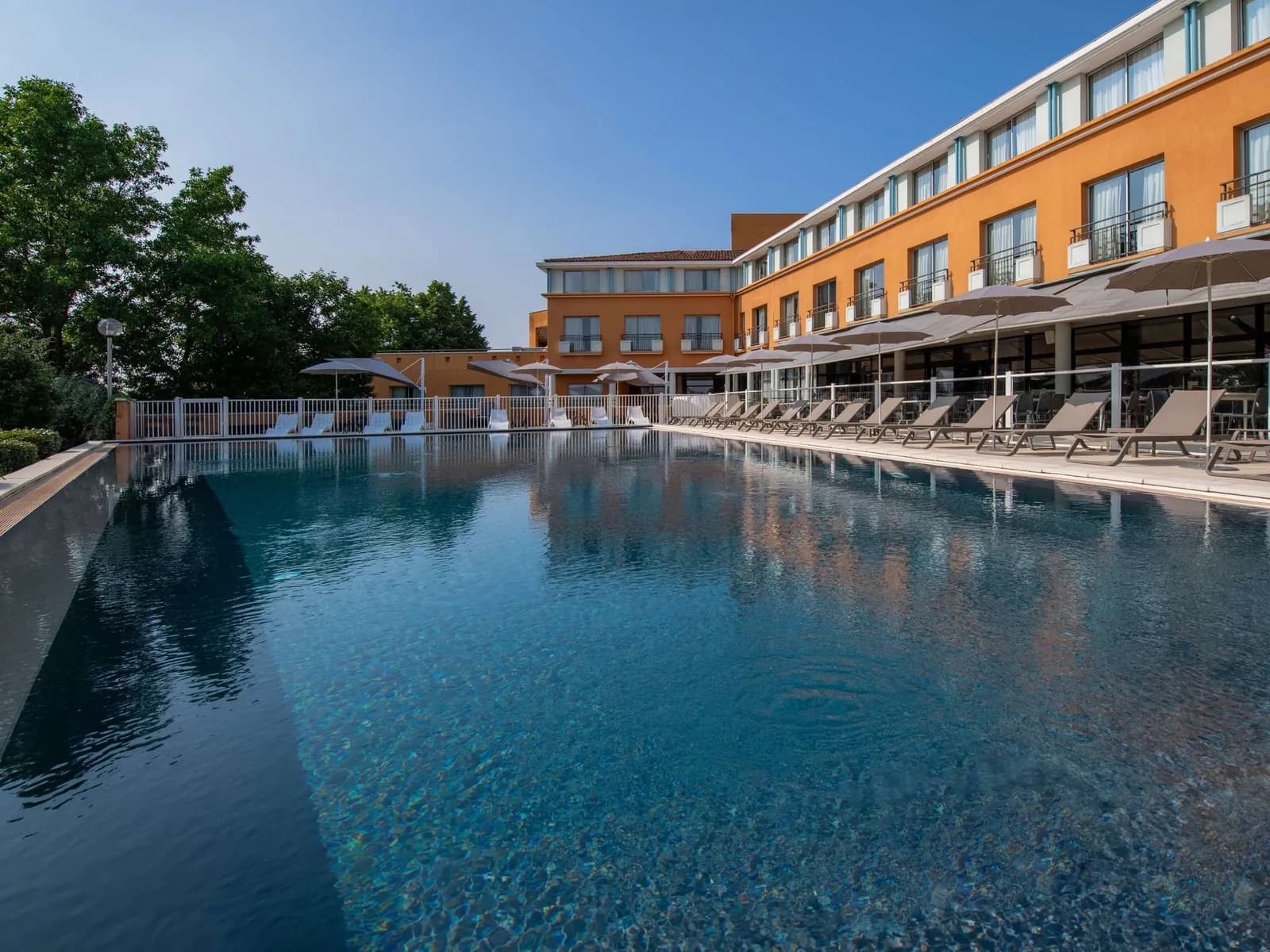 Outdoor swimming pool and terrace in front of the hotel at Mercure Toulouse Aéroport Golf de Seilh