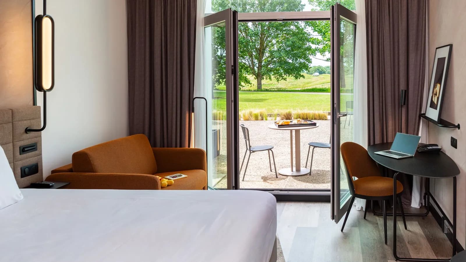 Guest room with a balcony door opening onto the lawn at Novotel Saint-Quentin-en-Yvelines Golf National