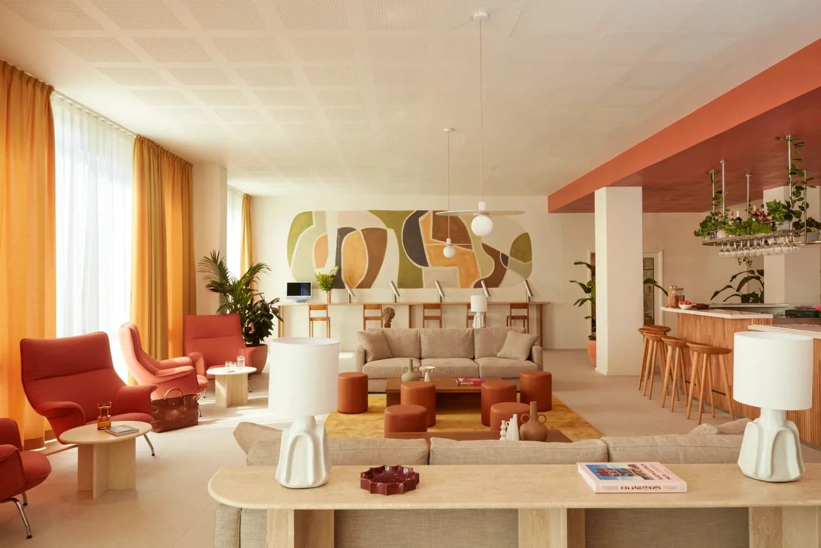 Lounge and bar of the OKKO Hotels Paris Rosa Parks with red armchairs, a wooden counter with high stools and warm curtains
