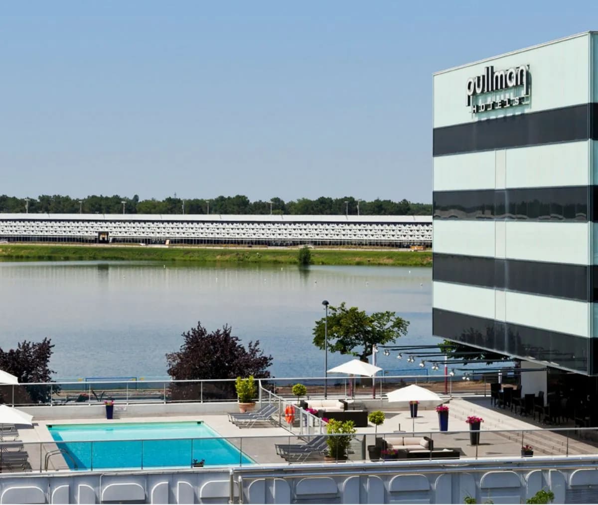 Pullman Bordeaux Lac hotel seen across the lake, with its striped tower and the outdoor pool on the terrace
