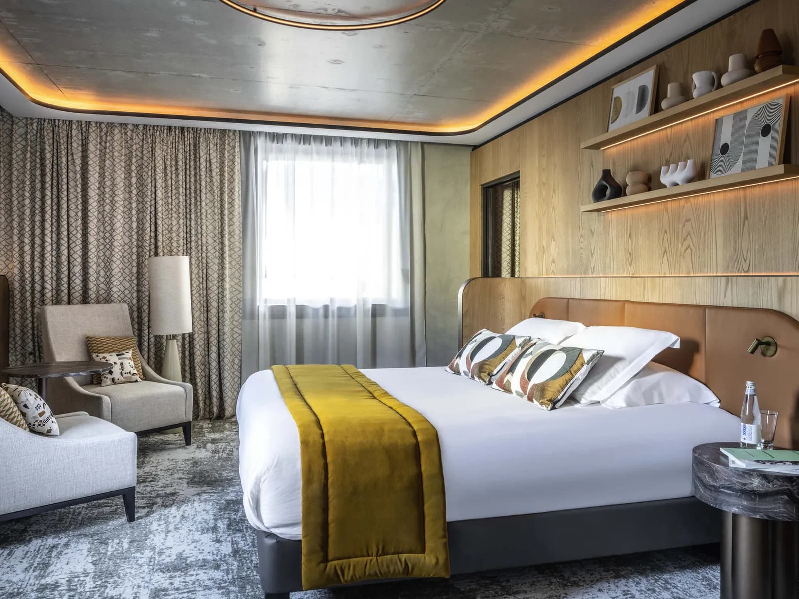 Guest room with a white bed, gold throw and wood-panelled walls at Pullman Lyon, Part-Dieu