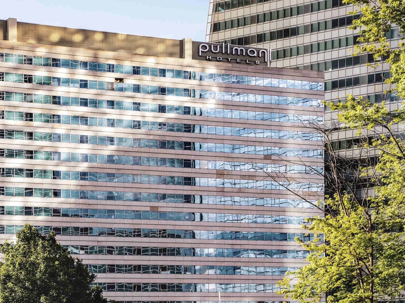 Glass facade and name sign of Pullman Paris La Défense hotel in the La Défense business district
