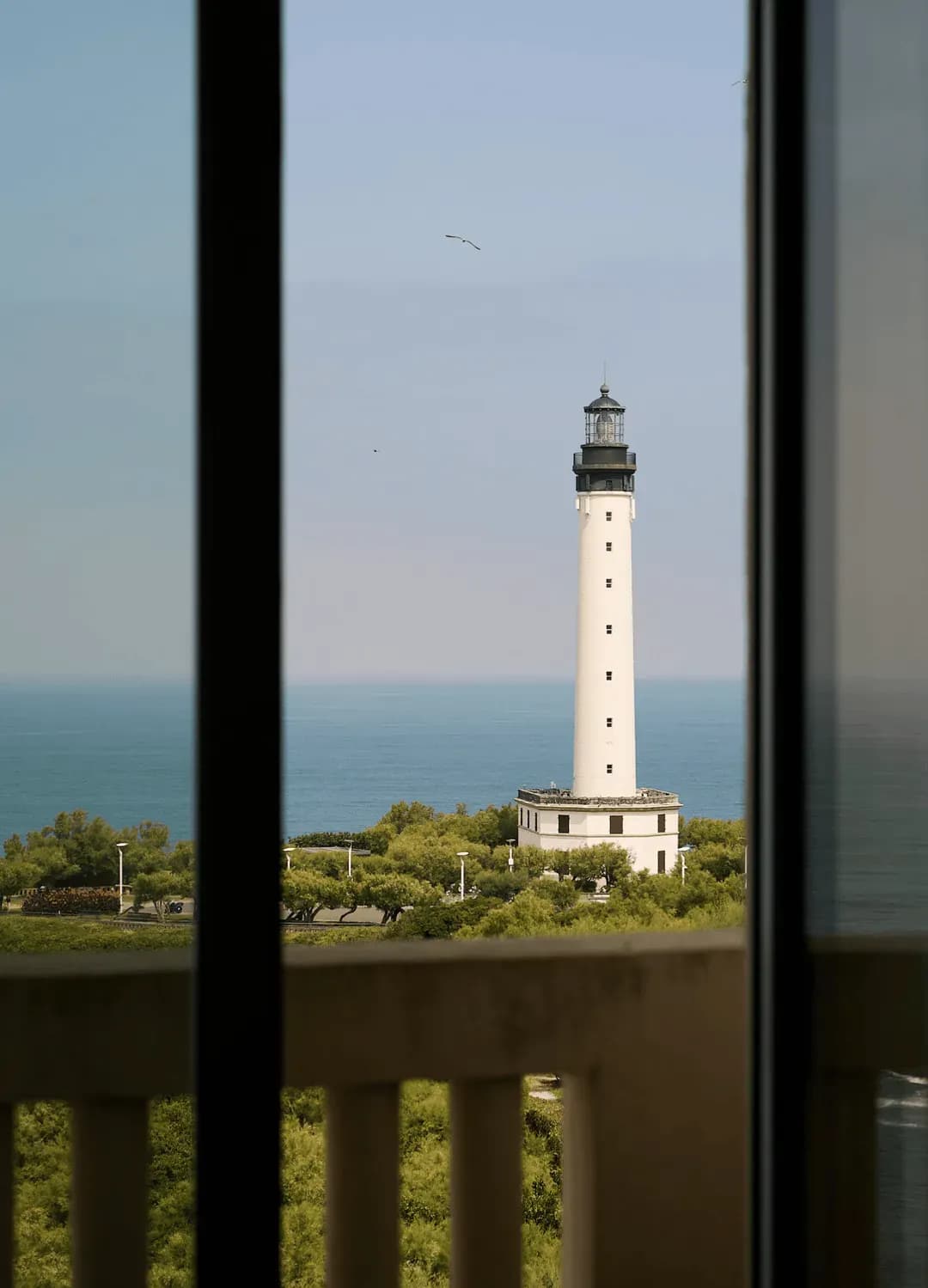 View of the Biarritz lighthouse framed by a window at Régina Experimental, Biarritz