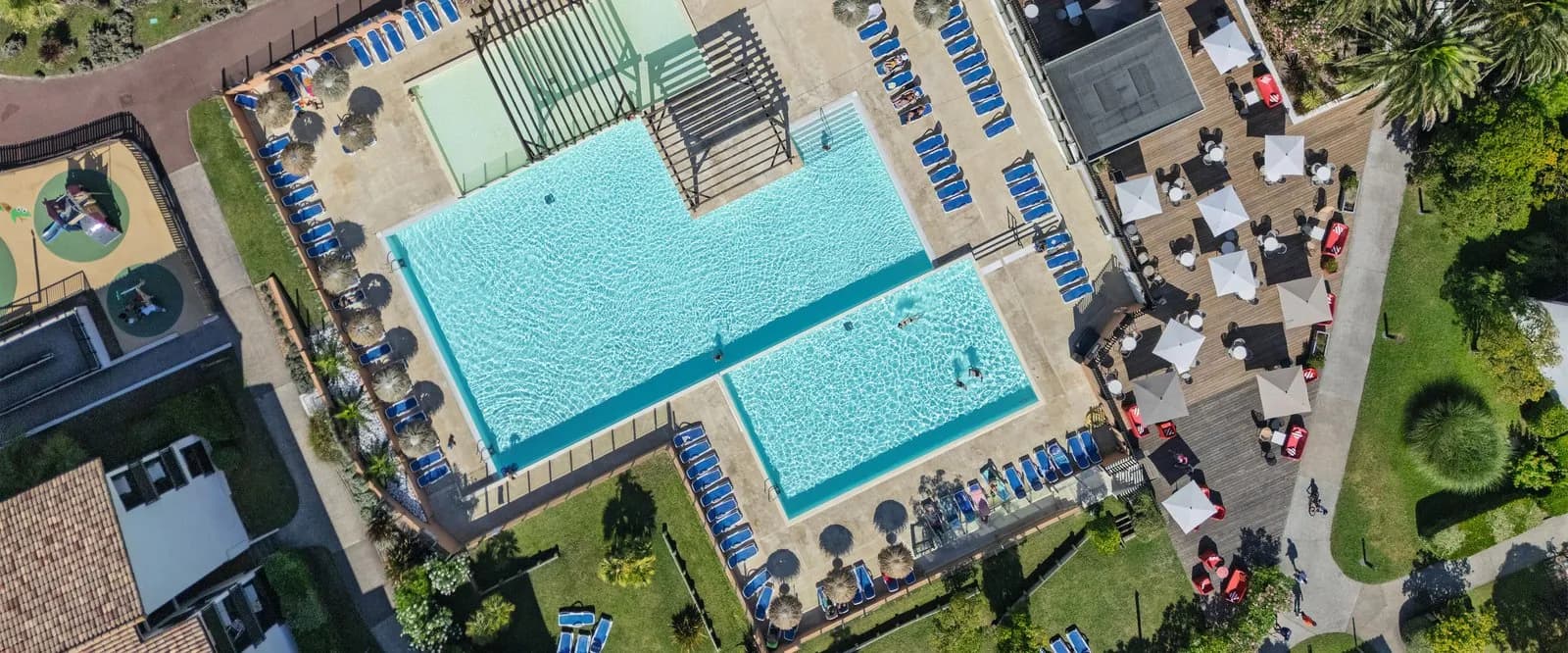 Aerial view of the heated pool with sunbeds and parasols on the lawn at Résidence des Dunes Argentées, Landes