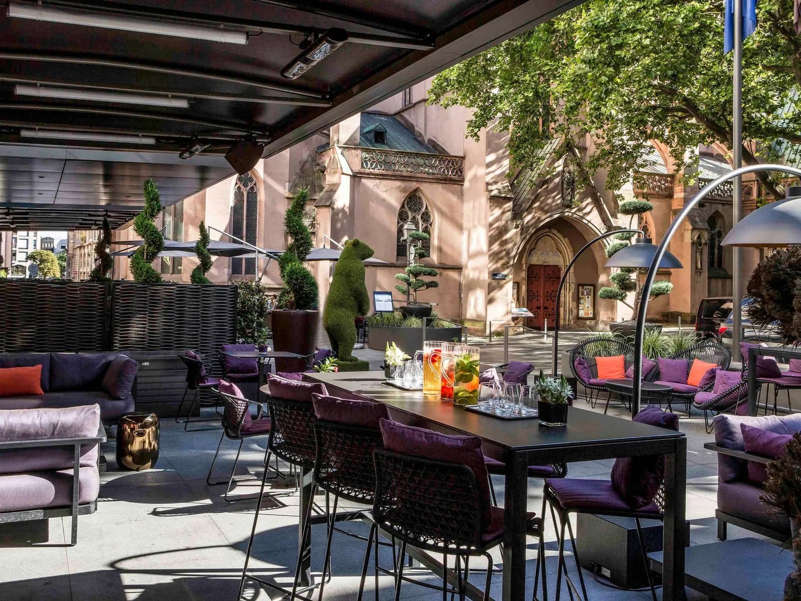 Terrace with purple lounge seats and a view of a Gothic church at Sofitel Strasbourg Grande Île