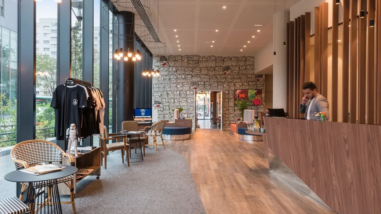 Reception of The Originals Boutique Hôtel Maison Montmartre, with light wooden floors and a stone wall