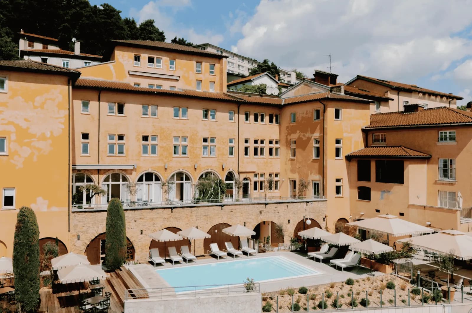 Pool terrace and sun loungers in front of the historic facade of Villa Florentine, Lyon
