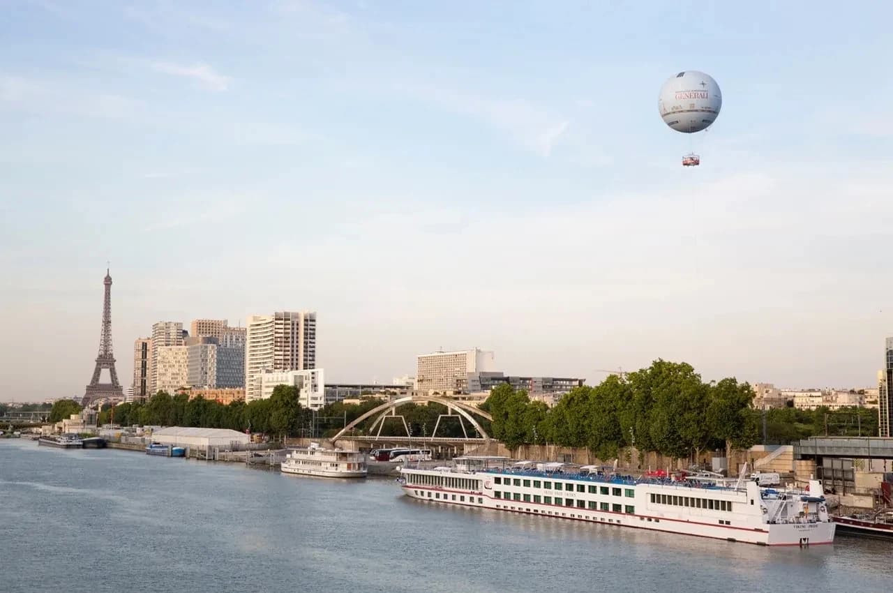 Seine riverside view with the captive balloon, the Eiffel Tower in the distance and a moored cruise boat.