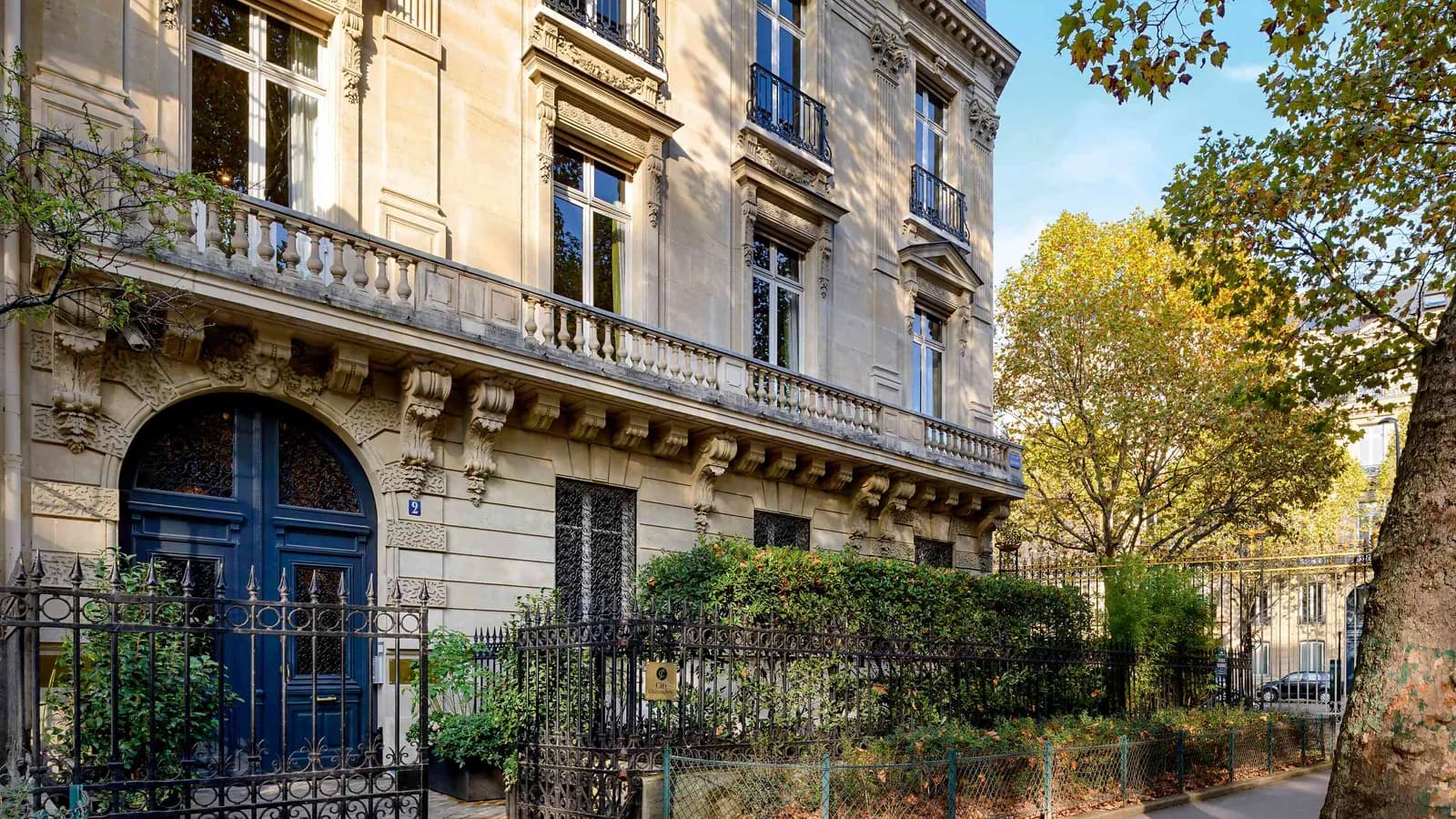 Discreet Circle townhouse facade with a blue door, tall windows and autumn trees