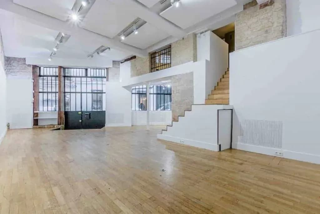 Long hall with black-framed windows, a wooden floor and a staircase to the mezzanine