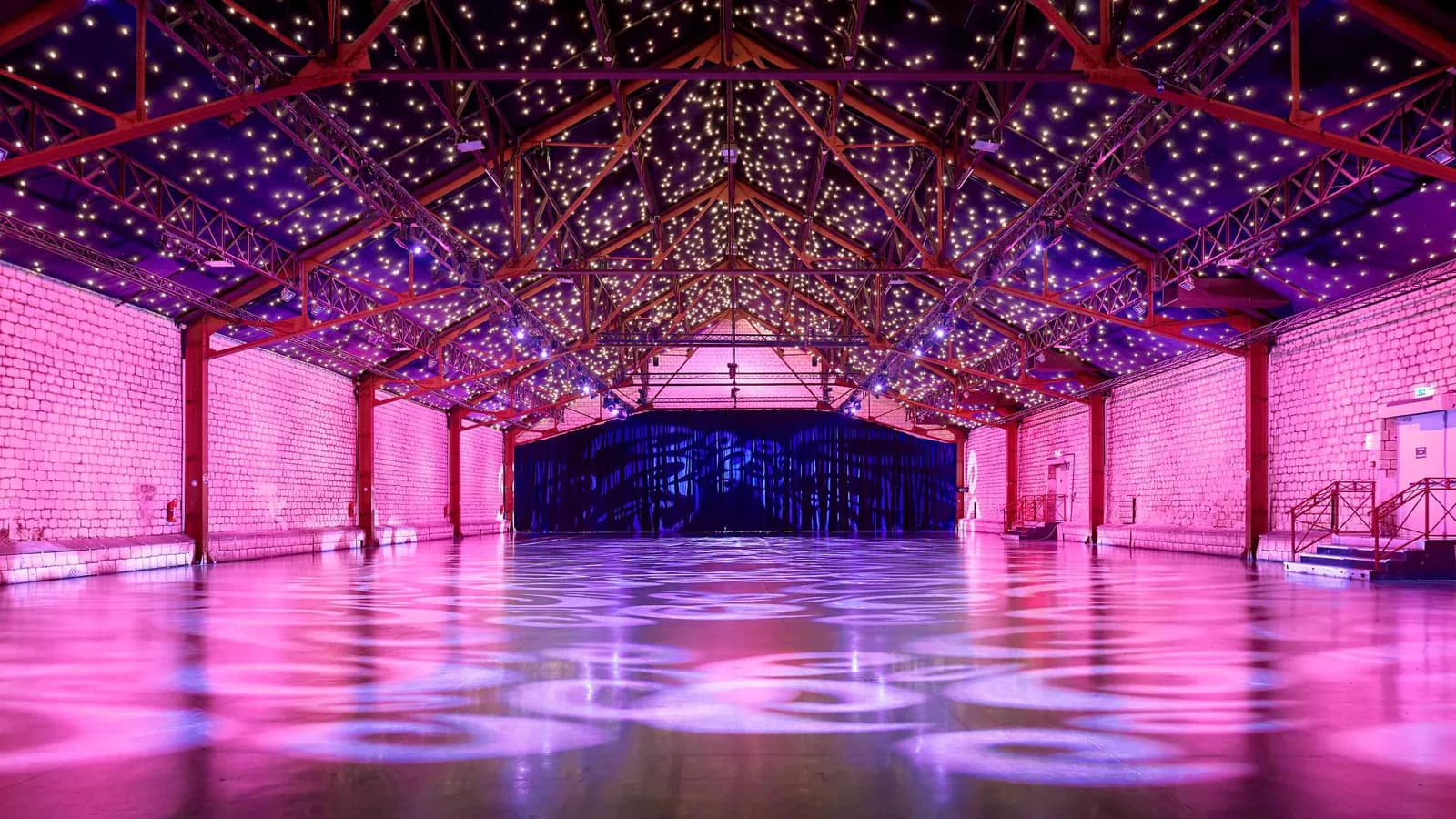 Seine Grand Halls main hall with a starry ceiling, exposed trusses and pink lighting