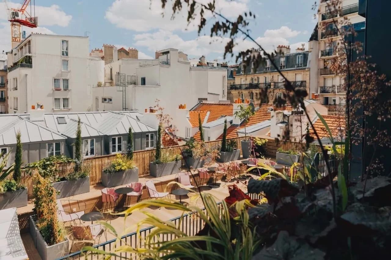 Rooftop terrace with planters and Parisian rooftops in the background.