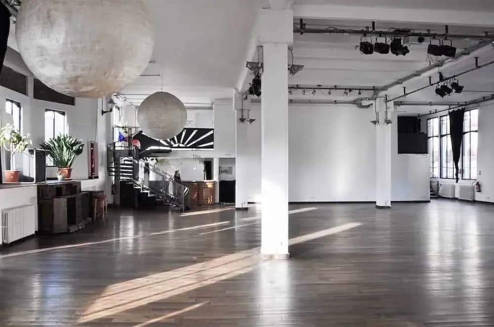 Large industrial hall with white columns, paper lantern lights and a wooden floor