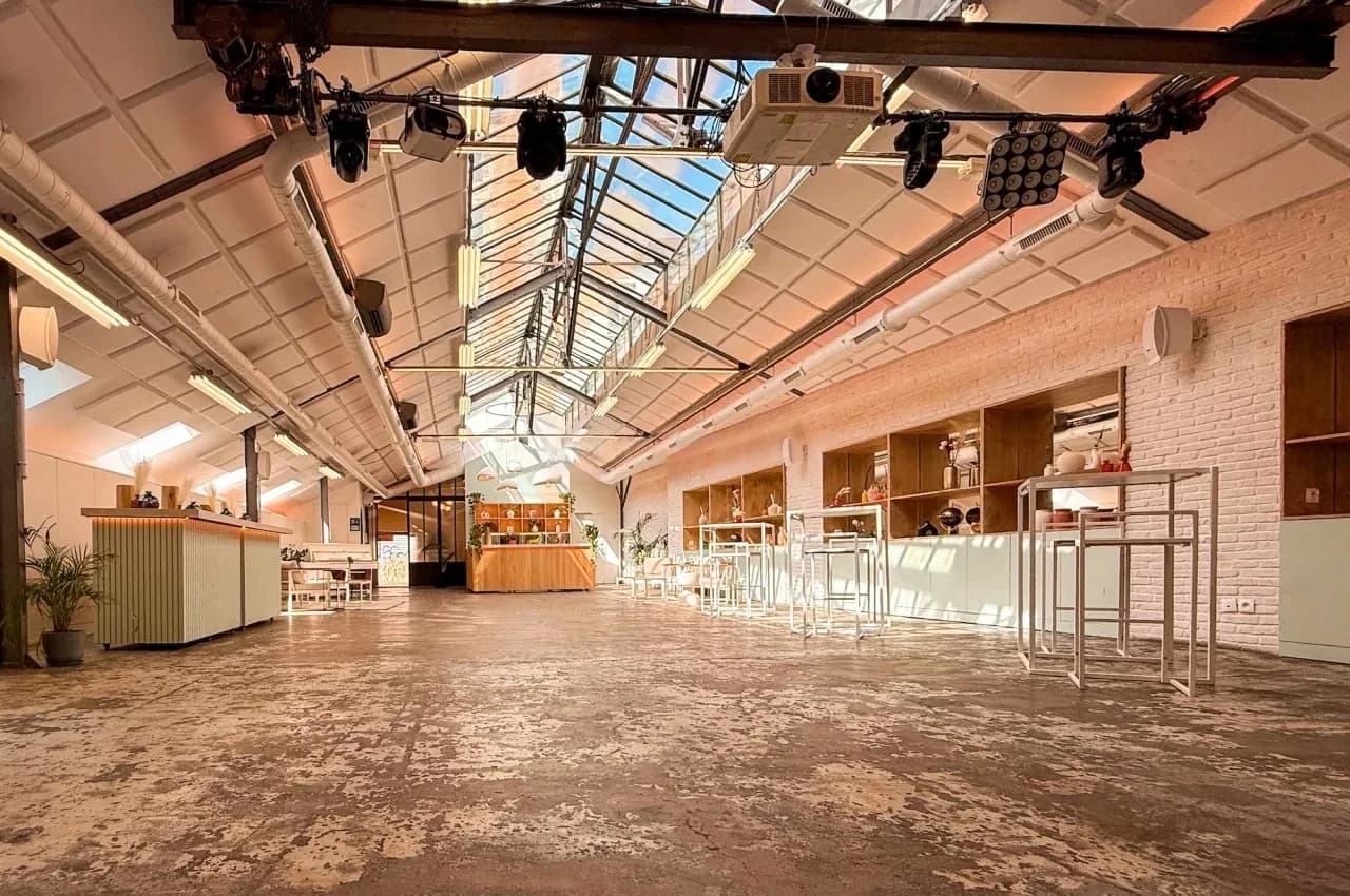 Long hall under a glass roof with stage rigging and daylight