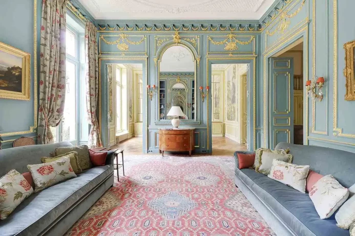 Salon with blue walls, decorative mouldings and a pink patterned rug
