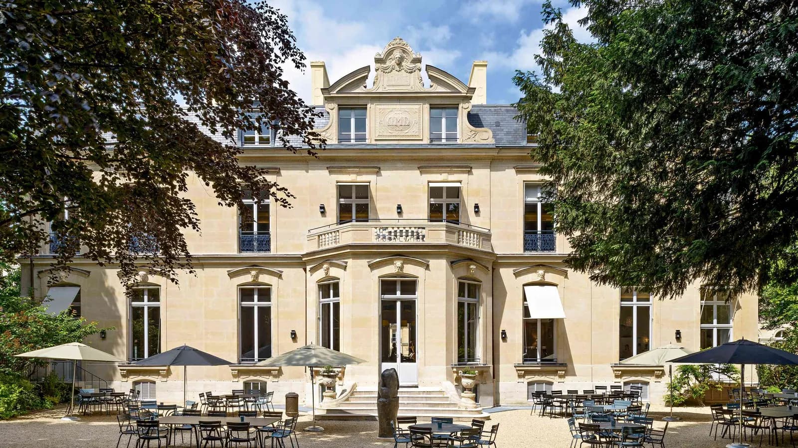 Moulding Salons Haussmann-style facade with a sunlit terrace of chairs and parasols in summer